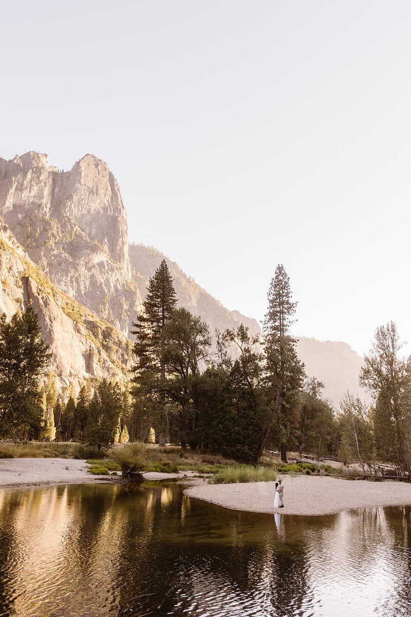 Couple holding each other on the shore of a Merced river in Yosemite Valley