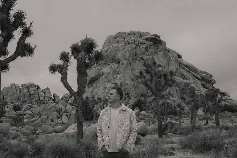 Todd standing among Joshua trees in a desert landscape, highlighting TM Photo Co’s wedding and lifestyle photography style.