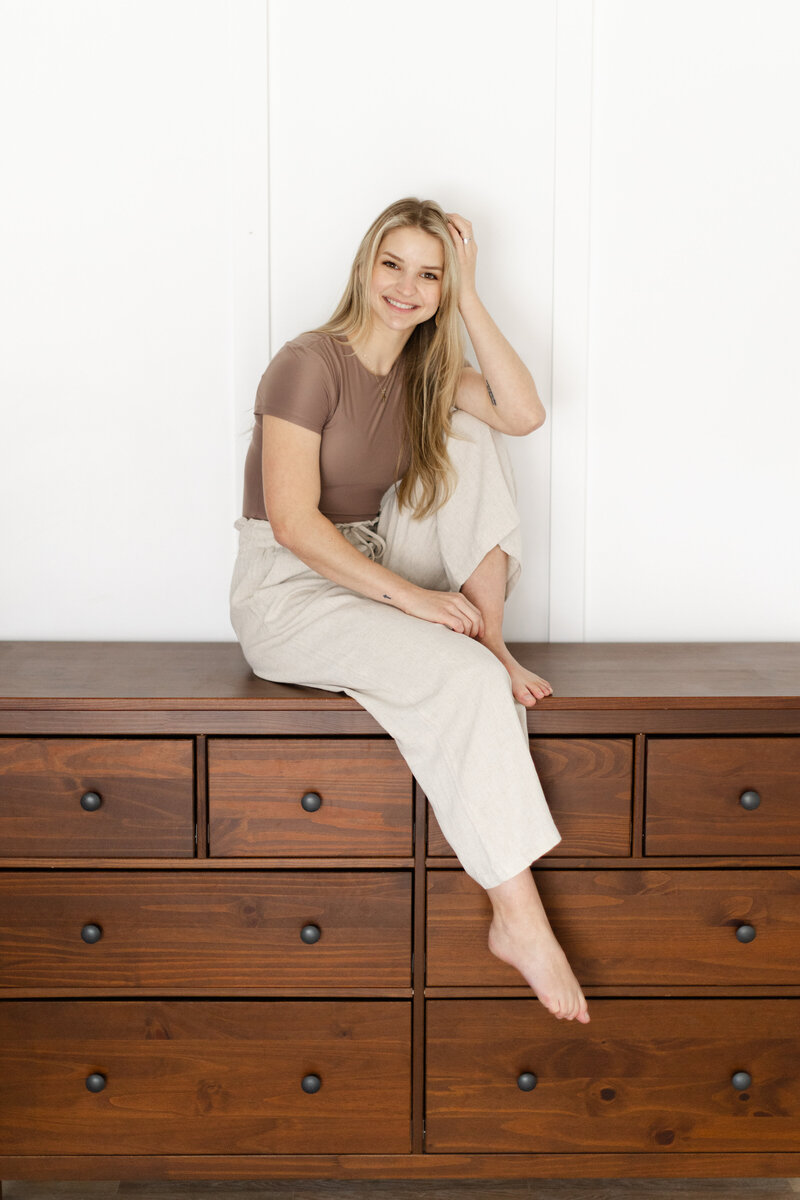 Sammie smiling while sitting on a wooden dresser