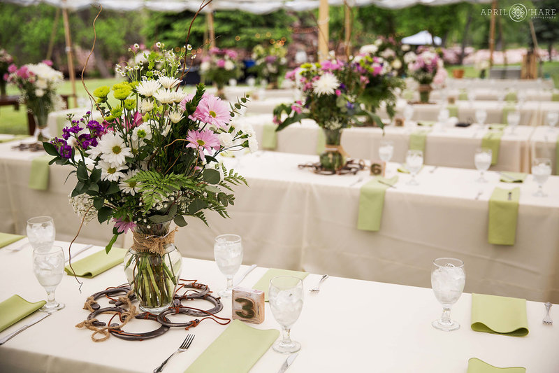 Long tables set up for wedding reception inside white tent at Riverbend wedding venue in Lyons