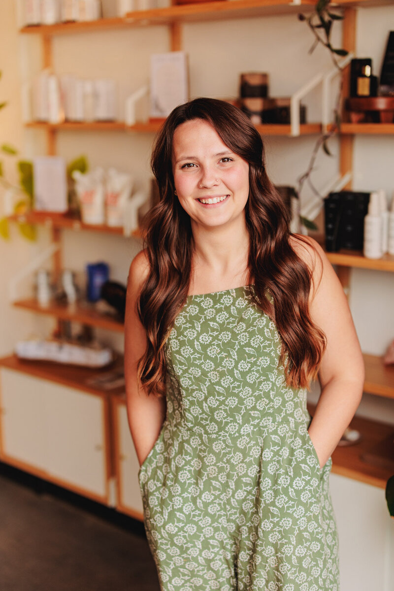 Yasmin a hair stylist in Eugene stands with her hands in her pockets and smiles at the camera.