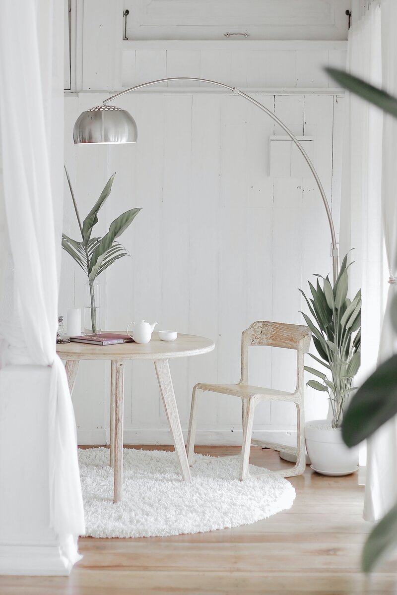 white room with plants and small table with chair