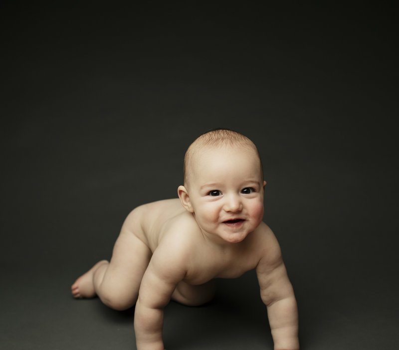 Baby dancing and giggling on colorful backdrop during one-year session