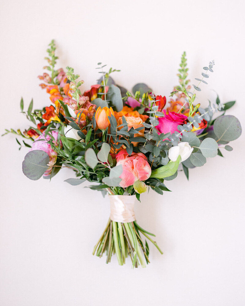 This vibrant layflat photograph showcases the bride's bouquet, featuring bold and beautiful colors. The striking floral arrangement captures the elegance and personality of the wedding day, creating a visually stunning composition.