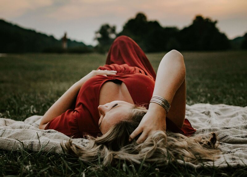A pregnant woman laying on a blanket in a field captured by a Pittsburgh maternity photographer.