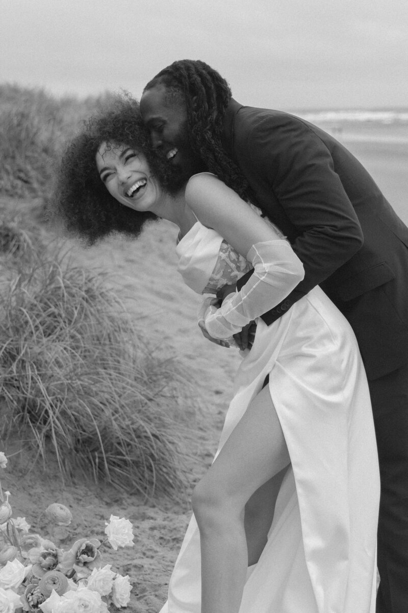 Black and white photo of a couple embracing and laughing on the beach