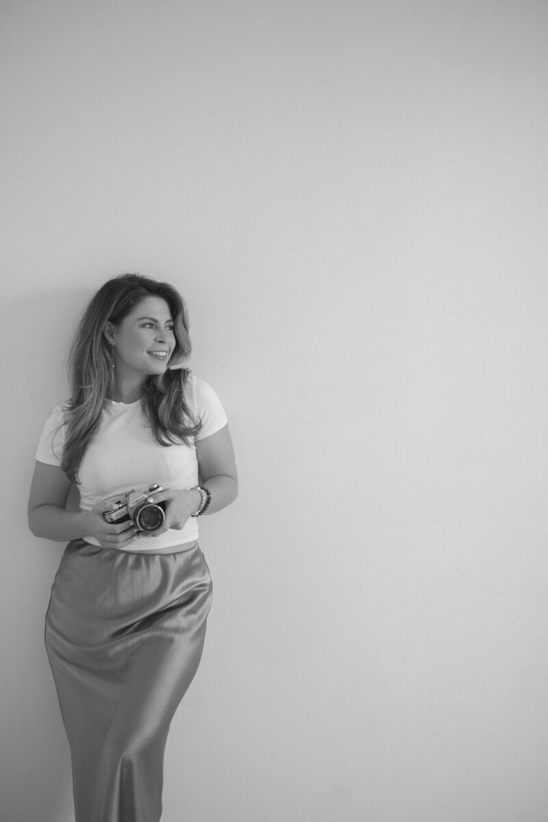 woman sitting on the beach smiling while holding a camera