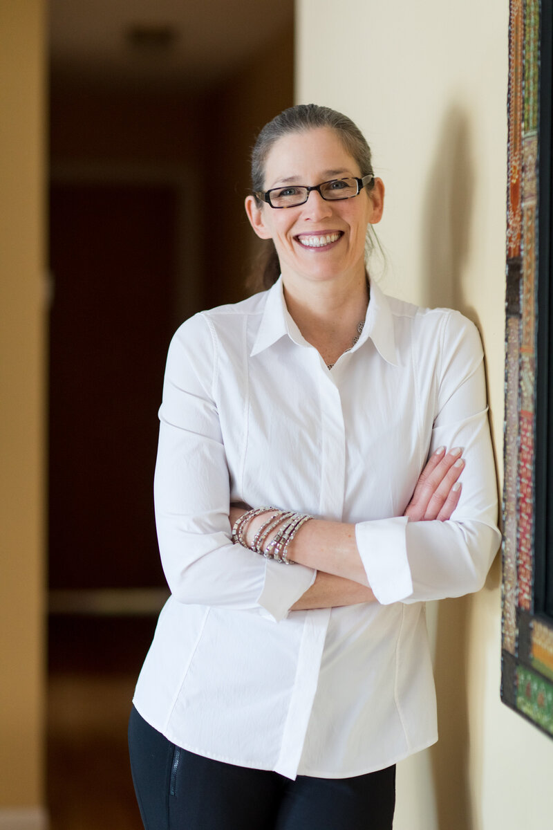 woman leaning up against a wall with her arms crossed smiling