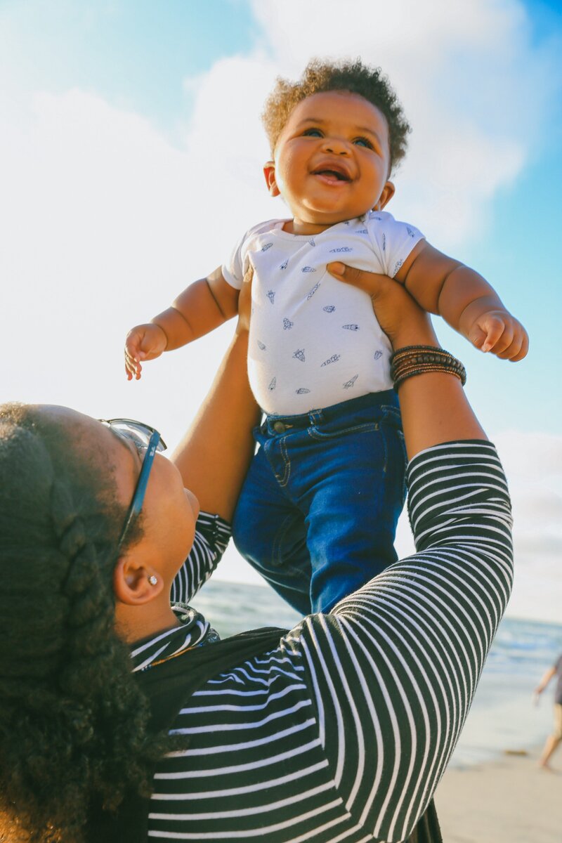 woman holding a smiling baby up in the air
