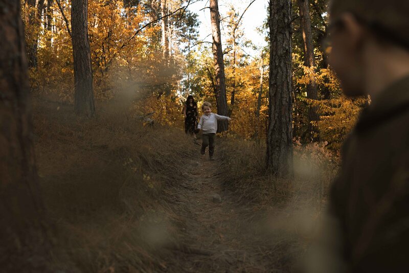 Family laughing together during a family session in a wooded area of the Black Hills.