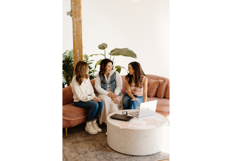 Empowered women in business collaborating around a table with a laptop