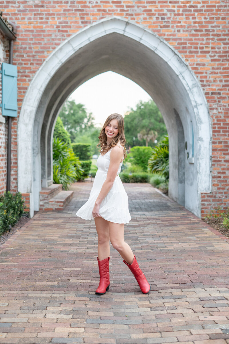 Khim Higgins Photography photographing an Oviedo senior girl wearing a white dress with red boots at Casa Feliz.