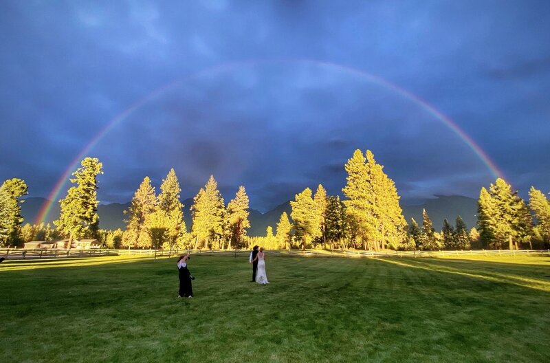 Montana wedding photographer photographing bride and groom under rainbow