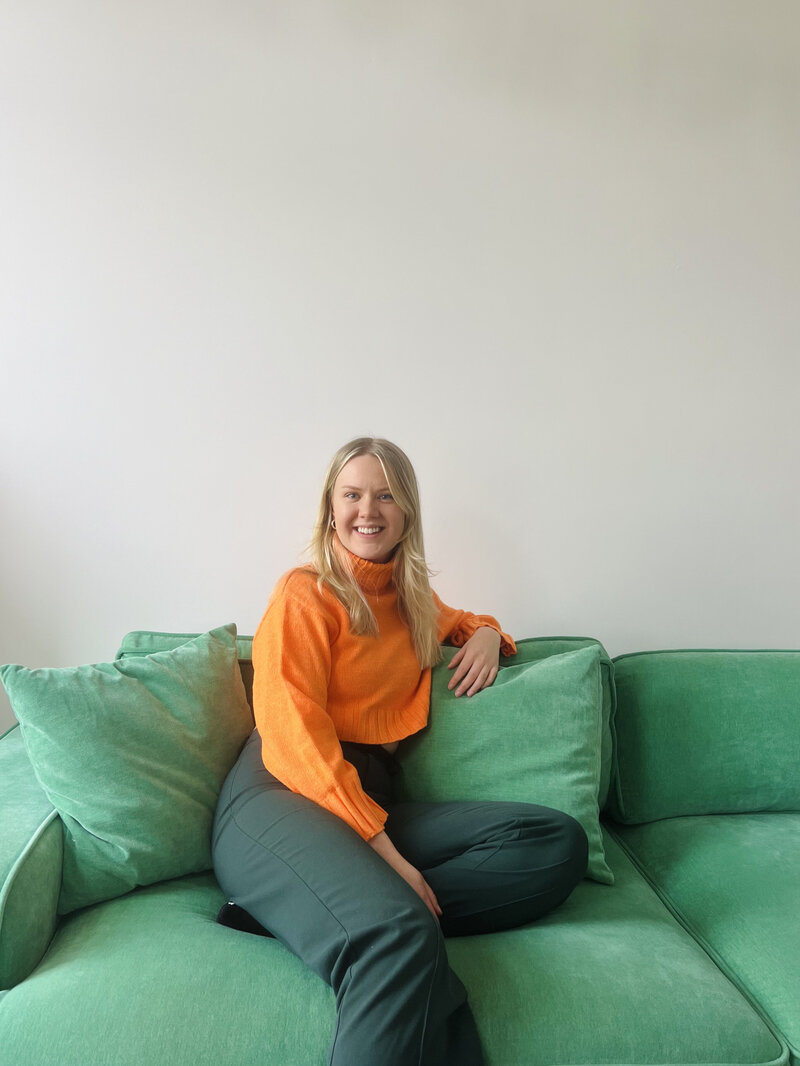 Sex Counselor on a green sofa smiling towards camera