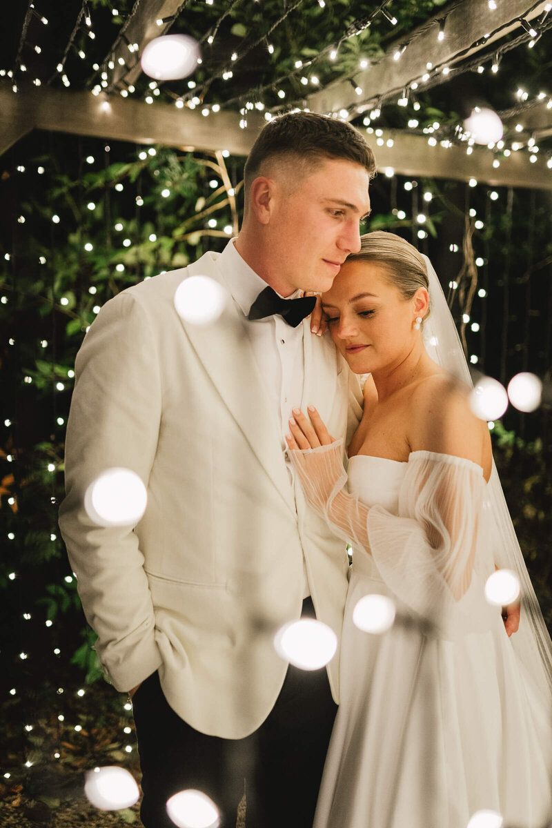 Romantic moment between the bride and groom under fairy lights at Caswell House