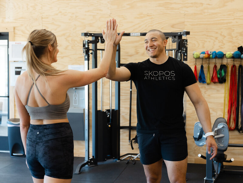 Gym members at Skopos Athletics in Dundas, MN, lifting weights during a strength training session.