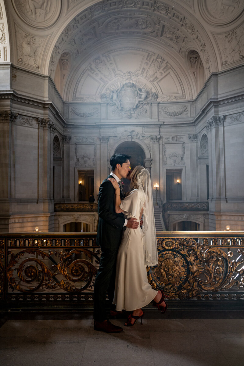 San Francisco Bay Area wedding photographer captures intimate City Hall moment with neoclassical columns and elegant balcony setting