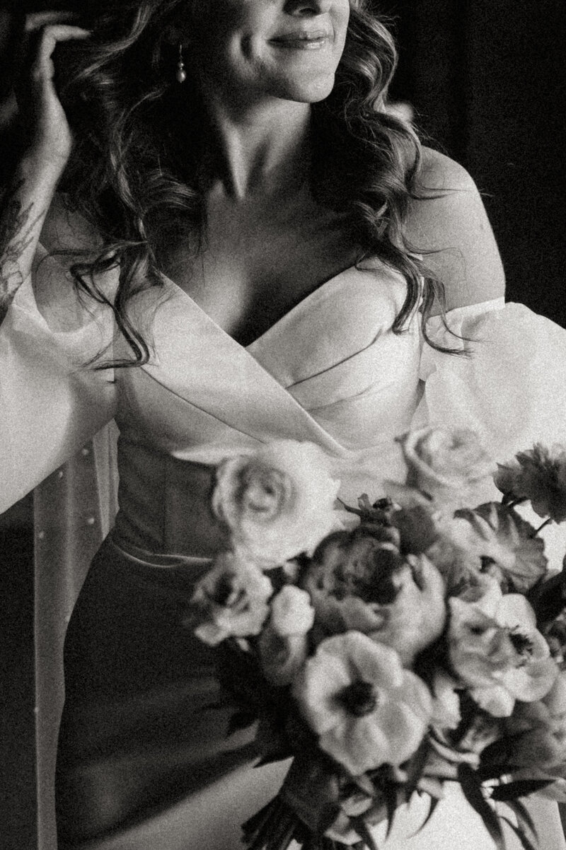A black-and-white close-up of a person in a wedding gown, holding a bouquet and smiling serenely in Chicago, Illinois.
