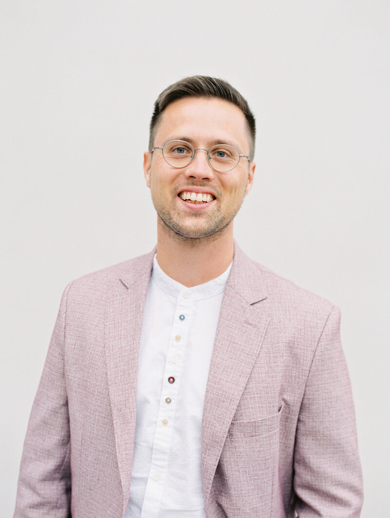 photographer, Ezechiel Theler, smiles for photo in pink tweed blazer and white button down shirt