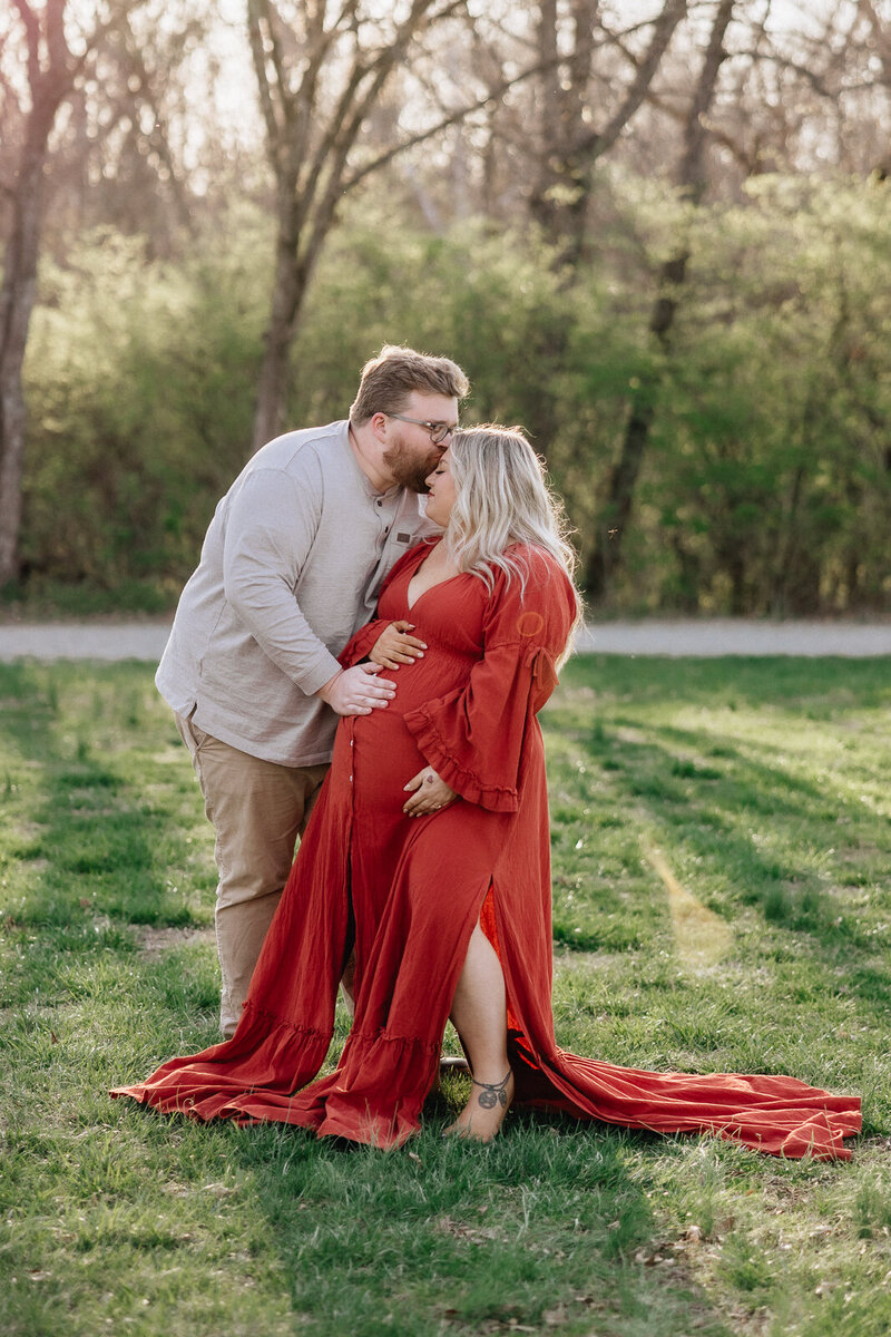 Expecting couple holding hands in a sunlit field during golden hour maternity session in Farmington Missouri.