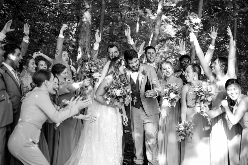 Bride and groom laugh and celebrate with bridal party at Whispering Trees wedding