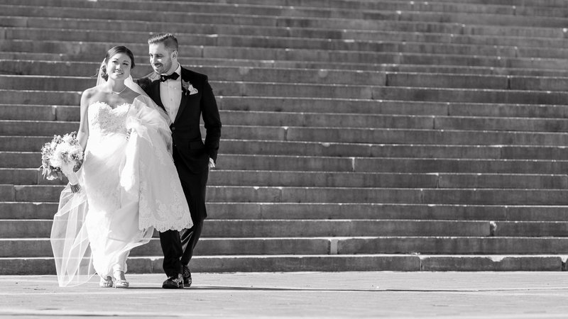 Bride and groom walking away together in a quiet moment at the Philadelphia Museum of Art, captured in black and white.