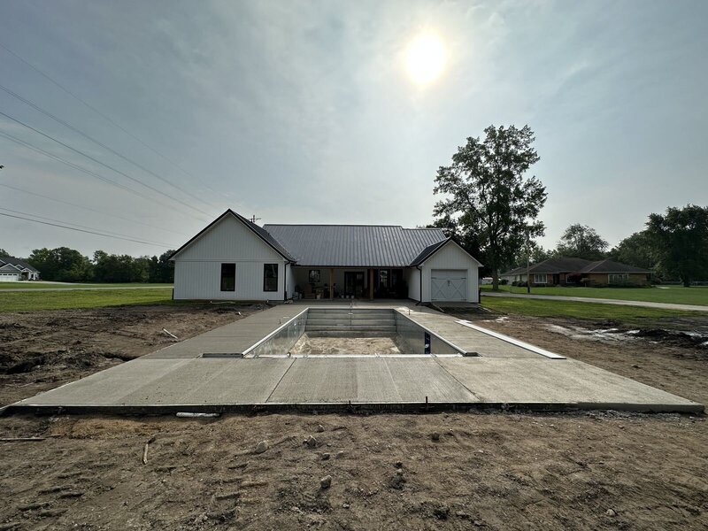 Finished concrete deck around a new pool behind a newly built home