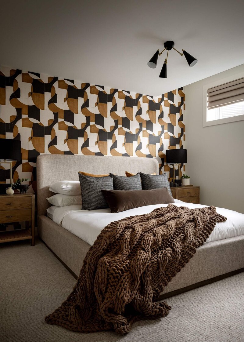 Inviting guest room styled with bold geometric wallpaper and accents of black and brown bedding. 