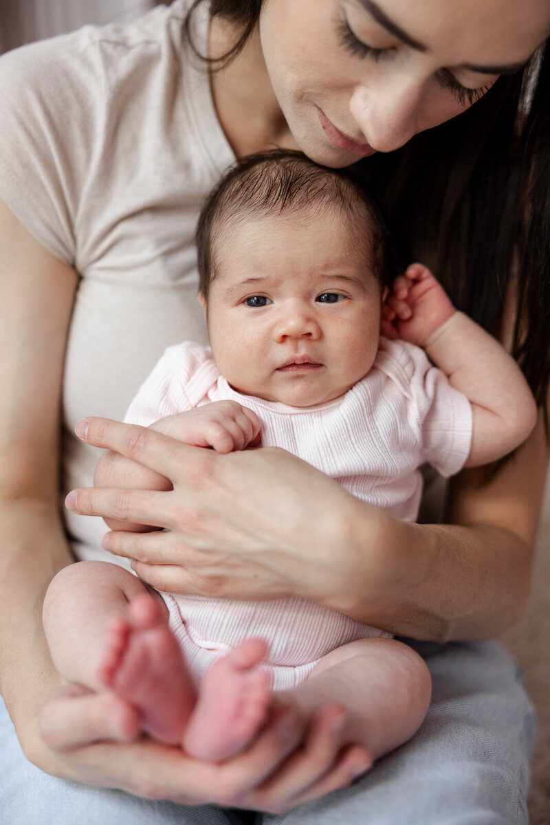 A mother holding a newborn infant on her lap cuddling and the newborn looking into the camera taken in De Soto, Missouri. 