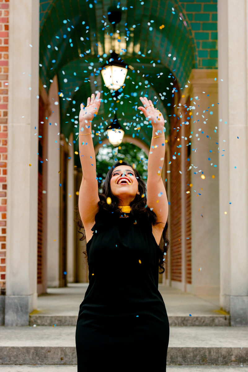 UNC graduate celebrating with confetti at the Bell Tower in Chapel Hill.