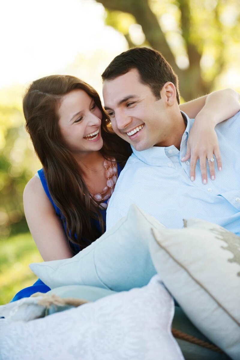 an attractive couple hugs while lounging on pillows in the grass