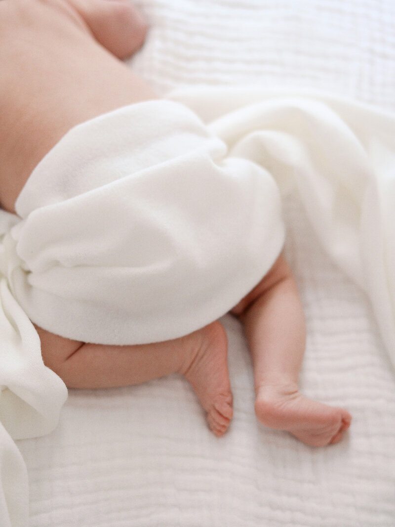 A close-up of the back of a baby wrapped in a white blanket at a newborn photography session in Richmond by Katie Stansfield Photography.