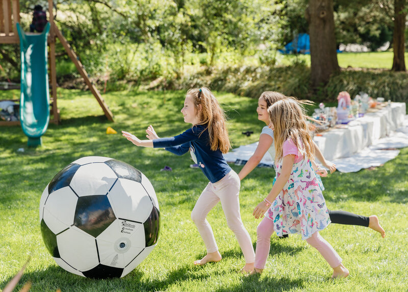Kids play with a giant soccer ball at a casual party.