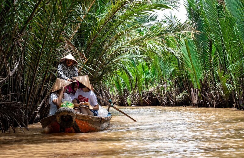 Vacationers on little boat on a river in Vietnam to show personal vacation planner services