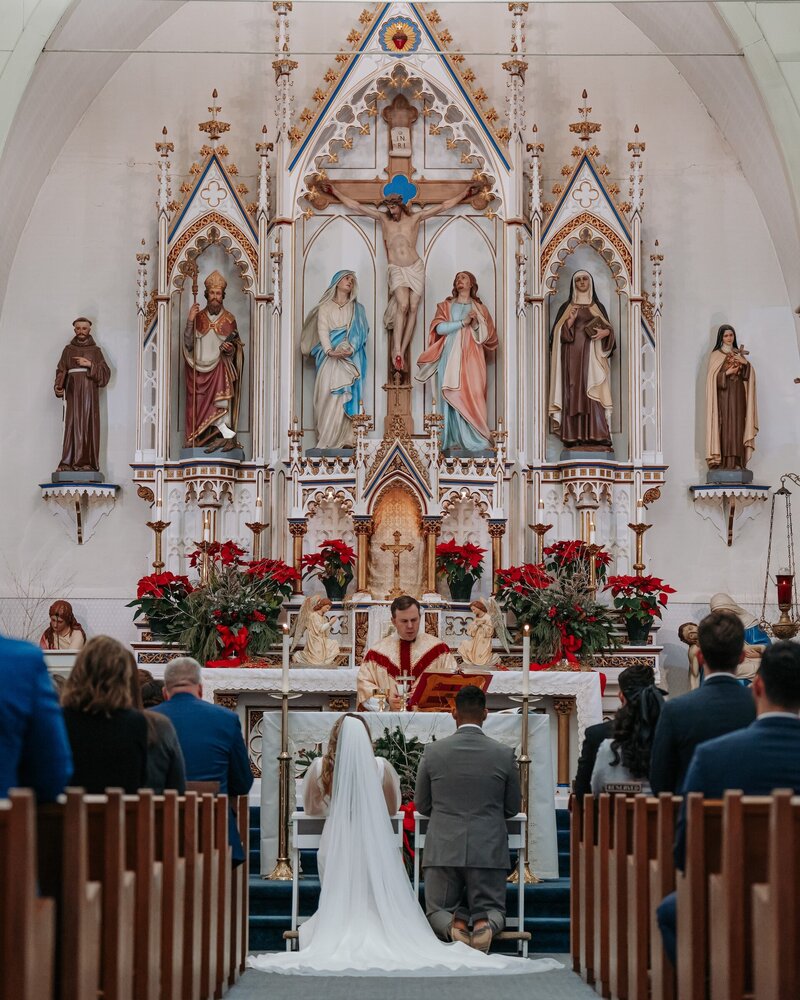 a bride and groom participating in a wedding ceremony in a Catholic church
