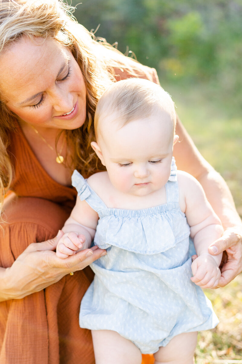 a mother holds her toddler helping them to walk during Minneapolis Portrait Session