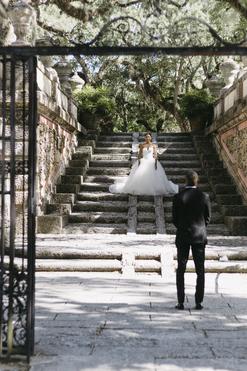 Bride on stairs, groom is looking at her from the bottom