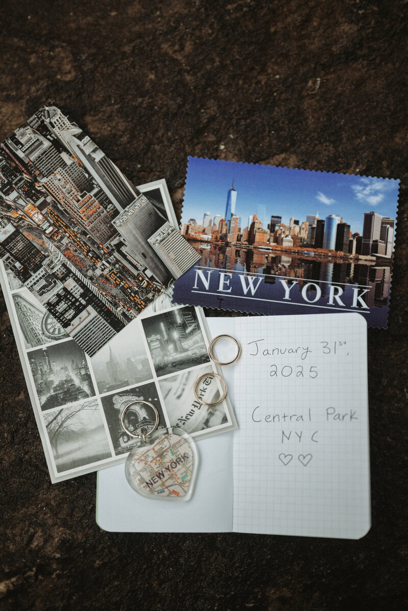 Flat lay of post cards, rings and a journal that included their vows.