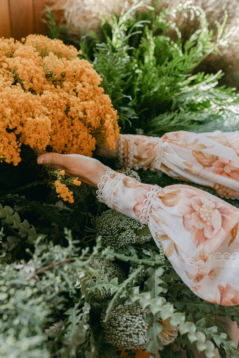 Hands reaching up and holding a orange flower bunch