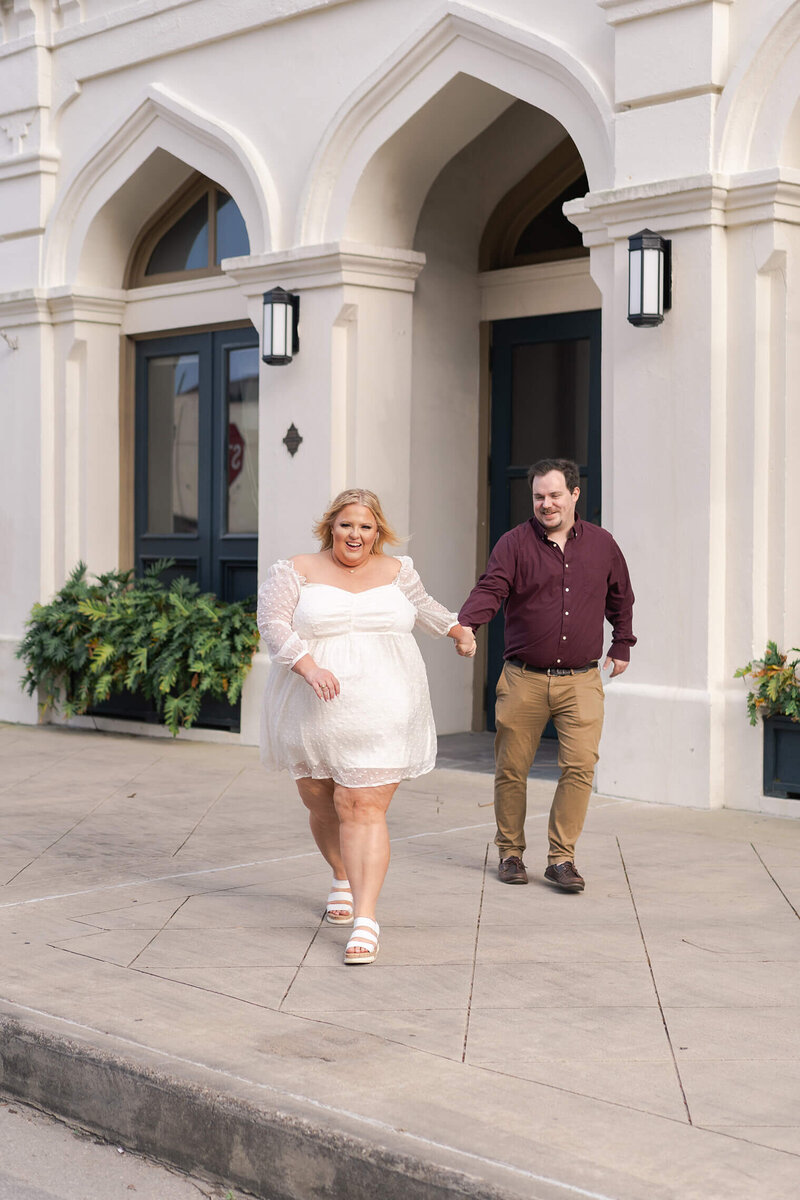 bride to be walks towards the street with her fiance during their engagement session at Hotel Tremont groom kisses bride to be on a rooftop in downtown Galveston by Swish and Click Photography