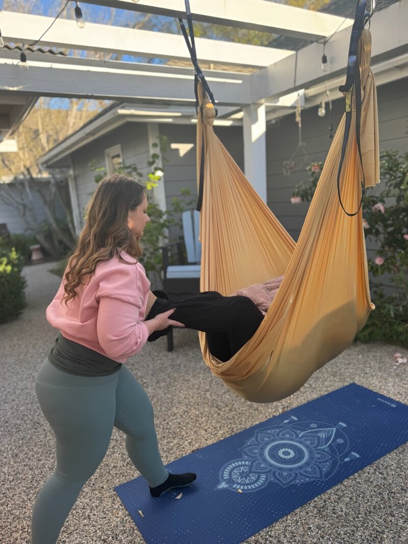Person receiving aerial somatic work in a somatic swing