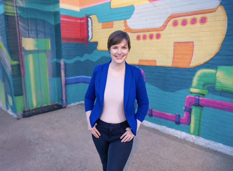 A-Baltimore-Business-Owner-Poses-during-headshots-in-Havre de Grace-Maryland-smiling-in-front-of-colorful-painted-mural