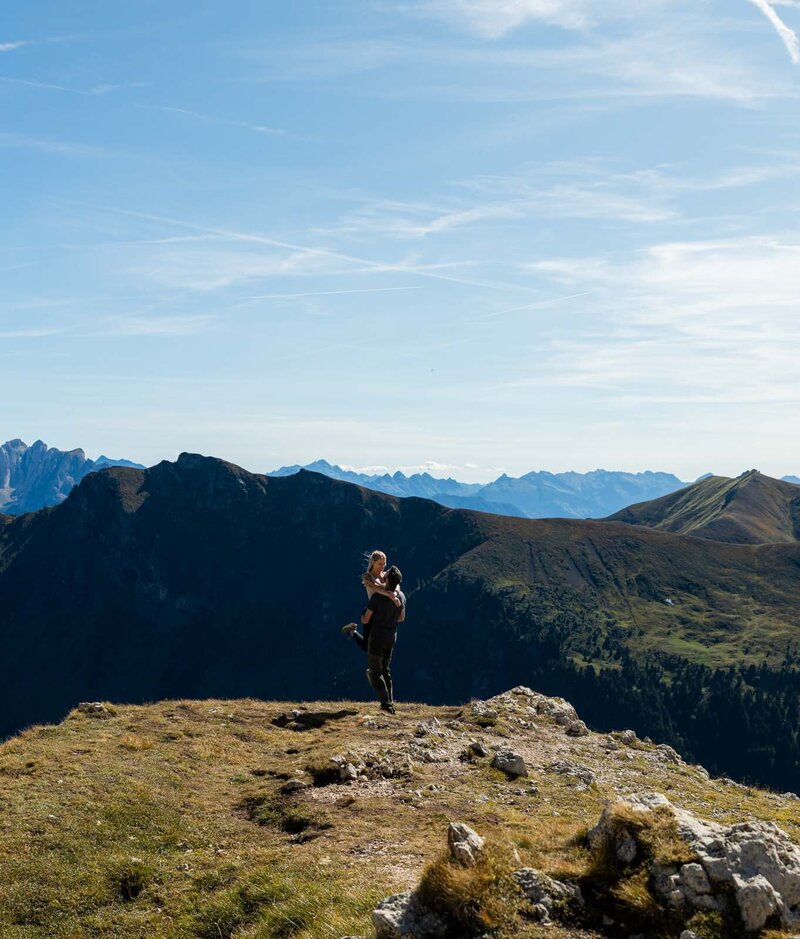 a couple embracing each other in front of the mountains of italy