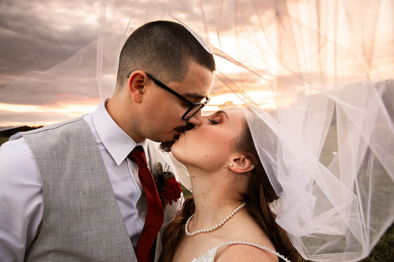 Close-up of bride and groom kissing a sunset