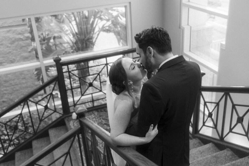 bride and groom share a kiss on the stairs