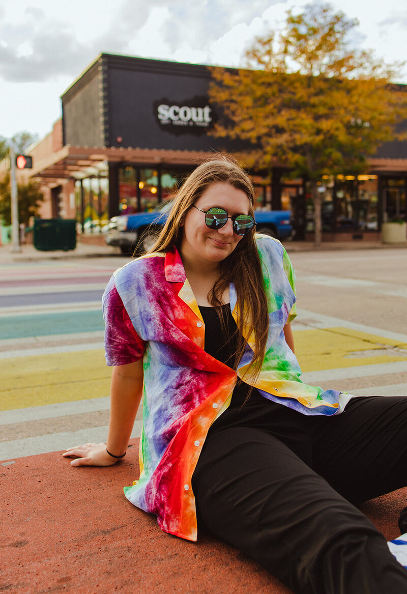 woman sitting on rainbow colored crosswalk