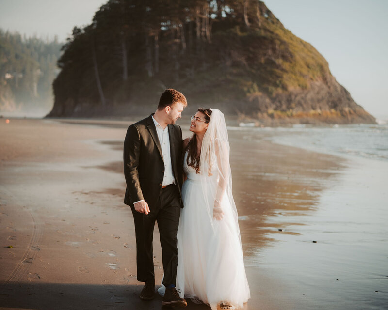 a newlywed couple walking on the beach