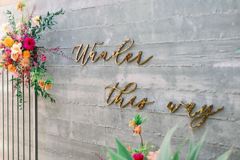 Gold letters on a wall that read, "Wander this way"