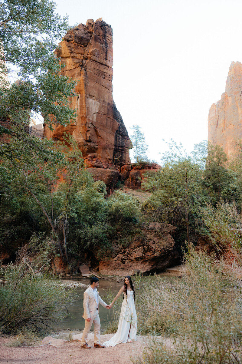 Couple walking hand-in-hand through Zion’s winding red rock trails.