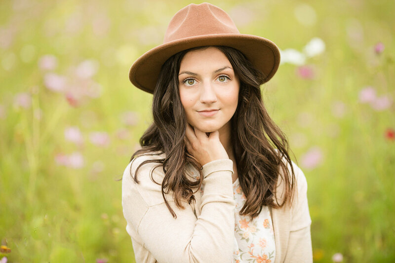 Girl wearing a wide brimmed hat, smiling.